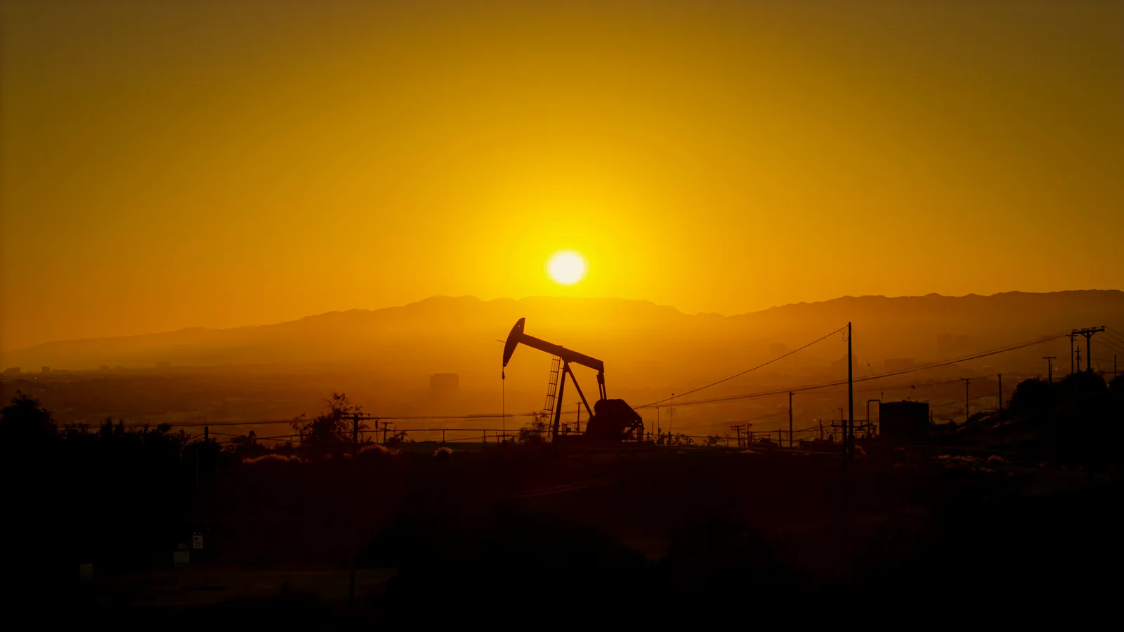 Oil pumpjack silhouetted against a hazy Los Angeles sunset
