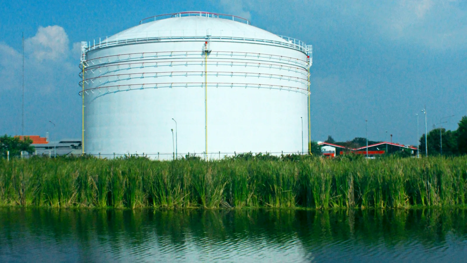 Large white oil storage tank beside calm water in Semarang, Indonesia